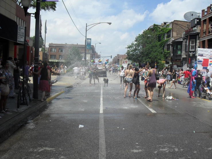 a group of people walk in the street as water spouts