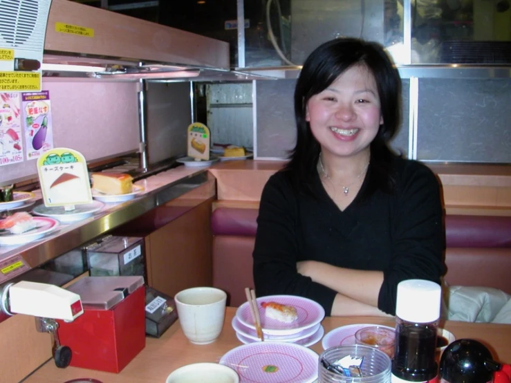 this is a woman sitting at a table filled with plates of food