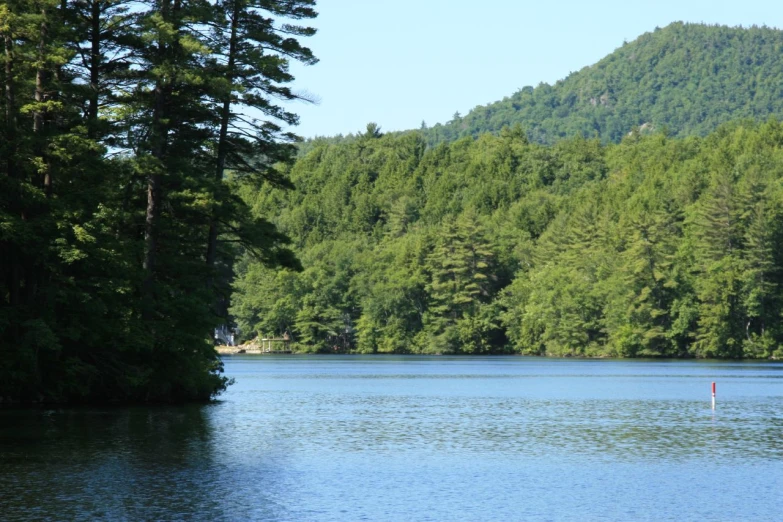 the view of a large lake from a distance with trees surrounding