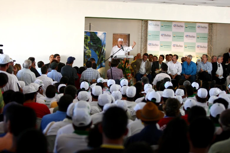 many people in white hats stand behind a panel