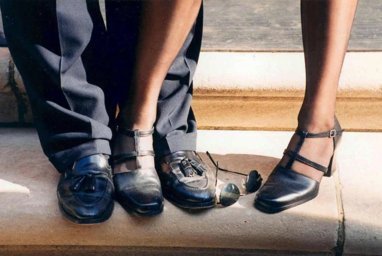 two people with wedding shoes on standing next to each other