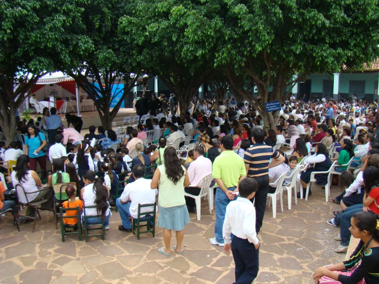 a crowd of people sitting and standing around a courtyard