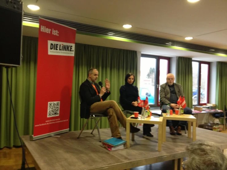 people sitting on a stage talking in a living area