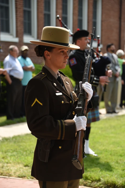 a woman in a uniform holds a rifle