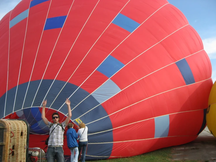 three people standing in front of a big red  air balloon