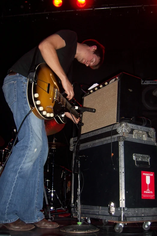 a man plays guitar on stage with his guitar case