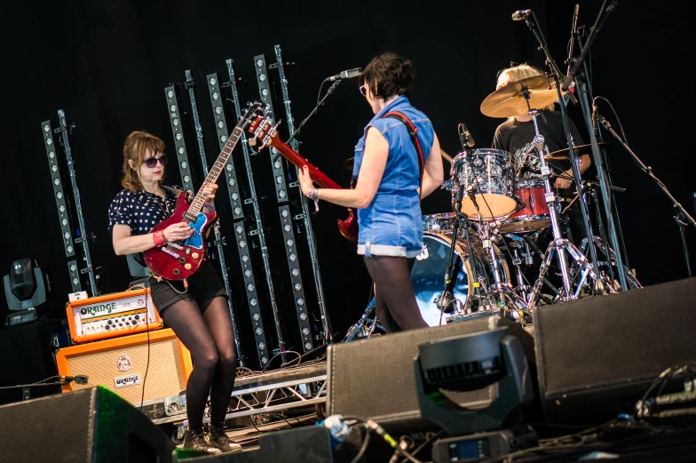 a woman standing on top of a stage with two guitar players