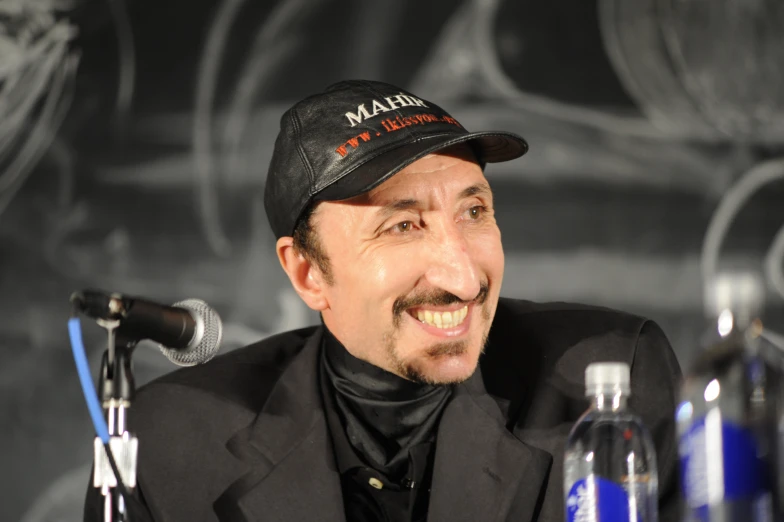 a man in a hat sitting next to a microphone