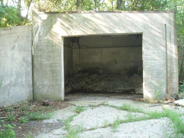 an unfinished concrete building with grass growing around it