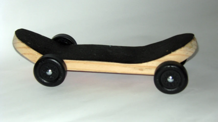 an empty black skateboard with black wheels sitting on a table
