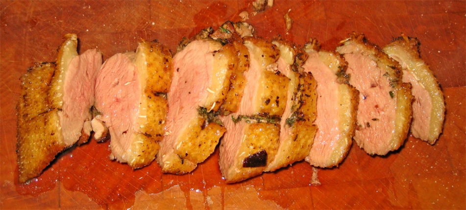 sliced meat sitting on top of a wooden table