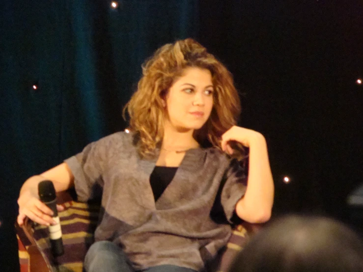 a woman sitting in a chair while talking to someone