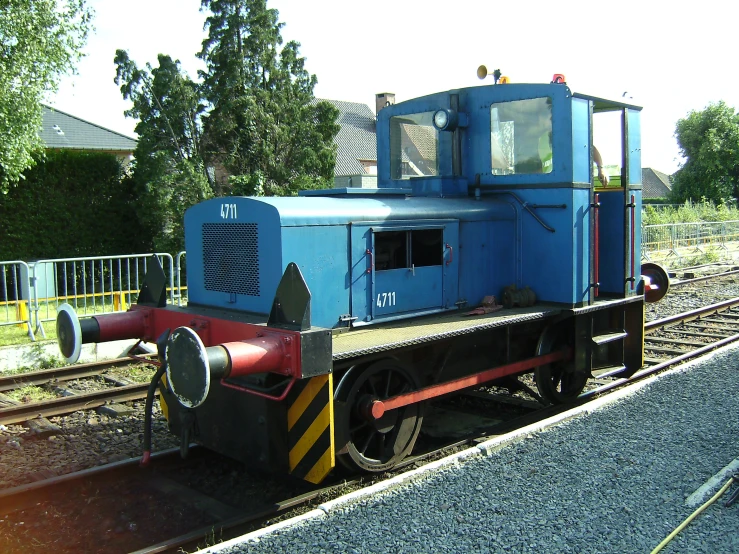 an old blue train on tracks in front of a house