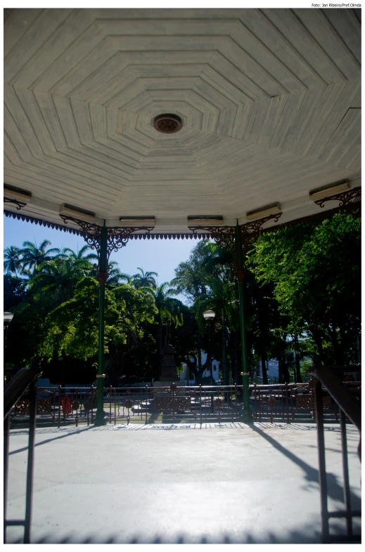 an umbrella sitting over some benches near trees