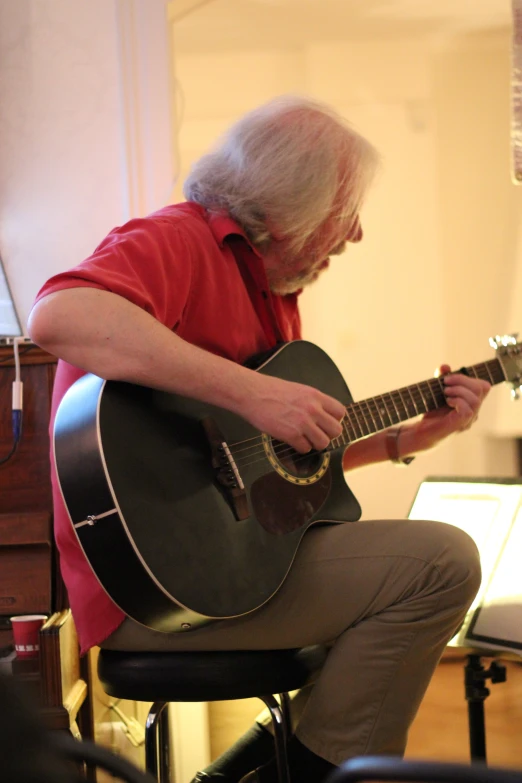 a man sitting on a stool playing a guitar