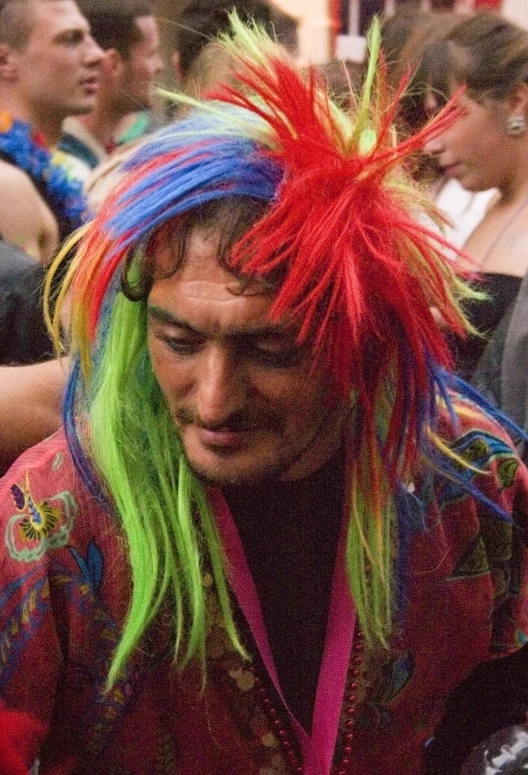 man with colored wig sitting at a table