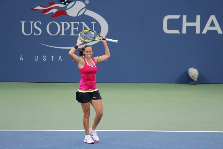 a woman holds up a tennis racket to serve the ball