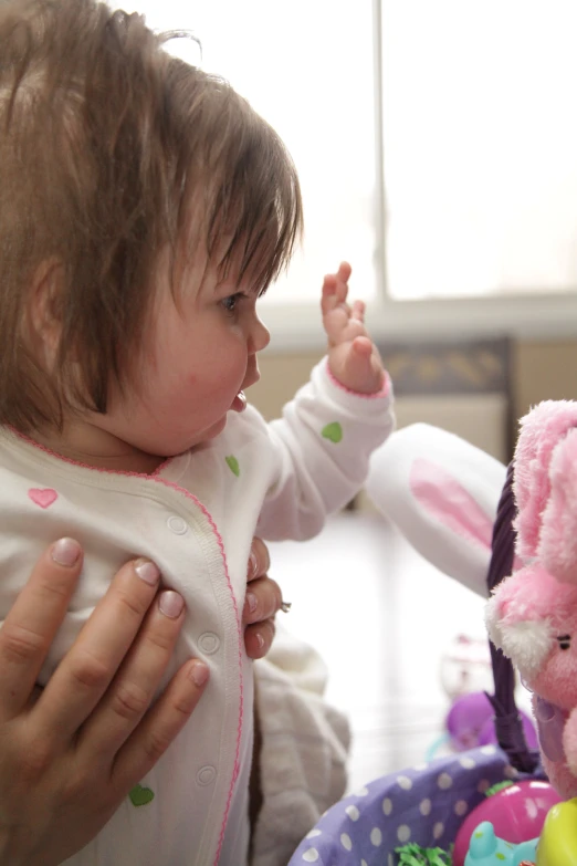 the young child is holding the teddy bear and touching it