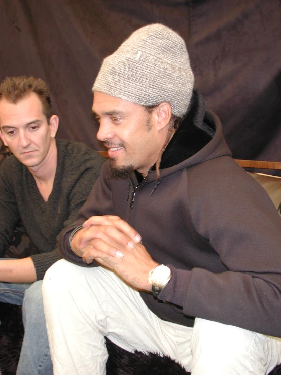 a young man standing next to a younger man sitting on a chair