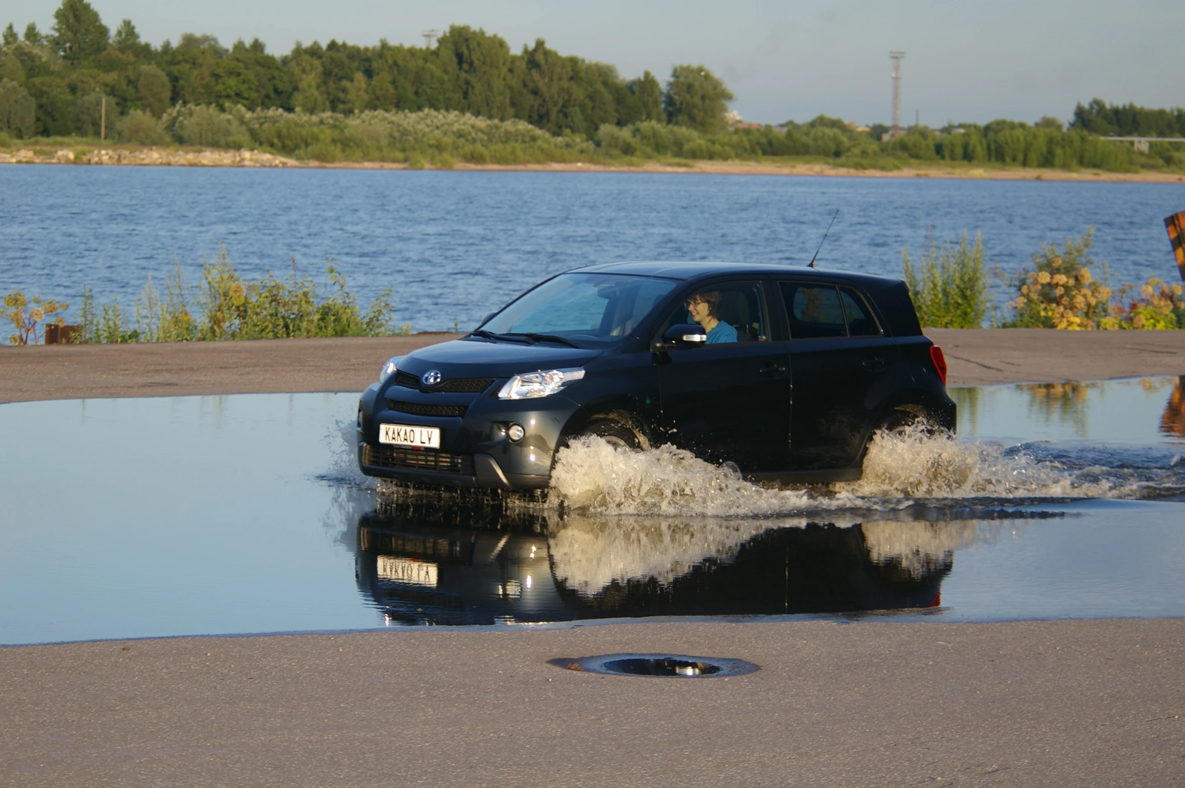 a black car is driving through a dle in the water