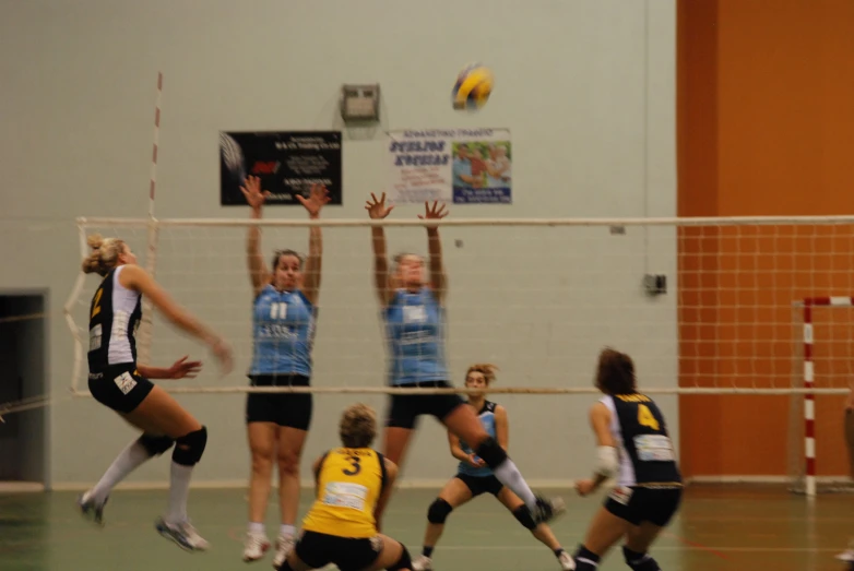 volleyball players try to catch a ball in a gym