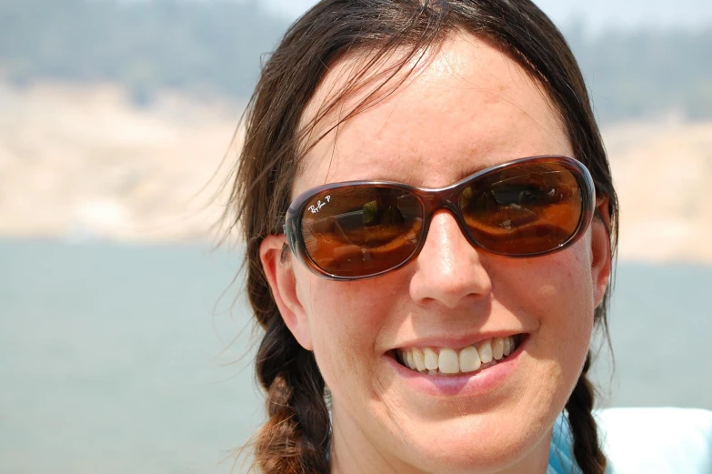 a close up of a person wearing sunglasses by water