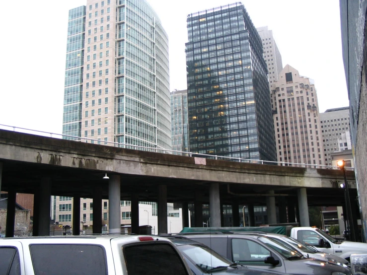 some cars are lined up on a road under an overpass