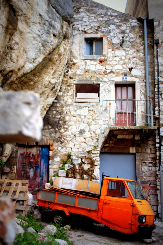 an orange truck parked outside of a building near a mountain