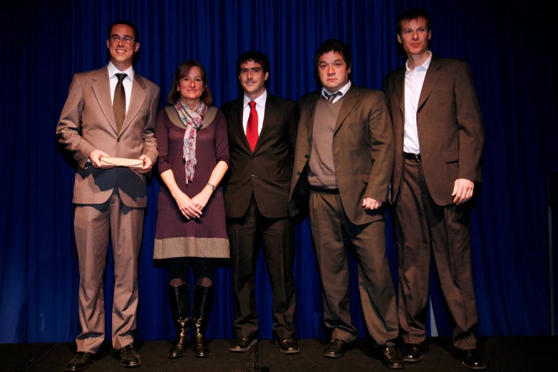 six people standing in front of a blue curtain with curtains