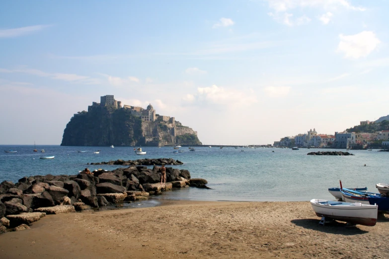 two boats sitting on the beach with an island in the background