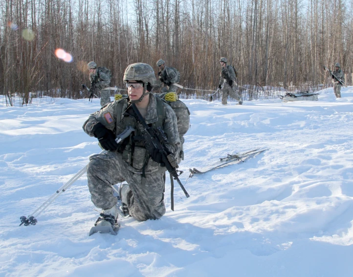 an army soldier holding onto his rifle in the snow