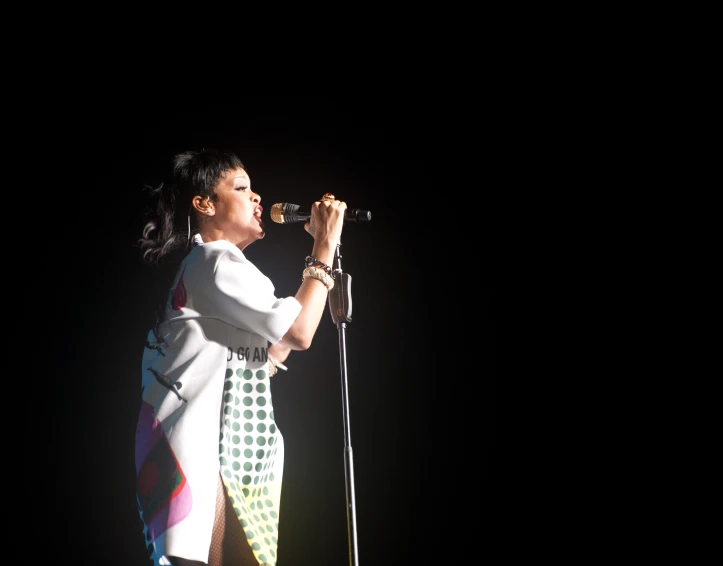 a woman in white shirt on stage with a microphone