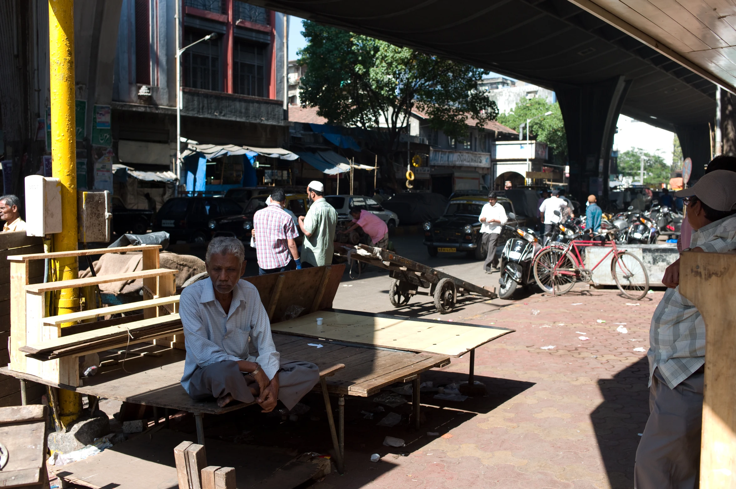 an old man sitting on a bench next to traffic