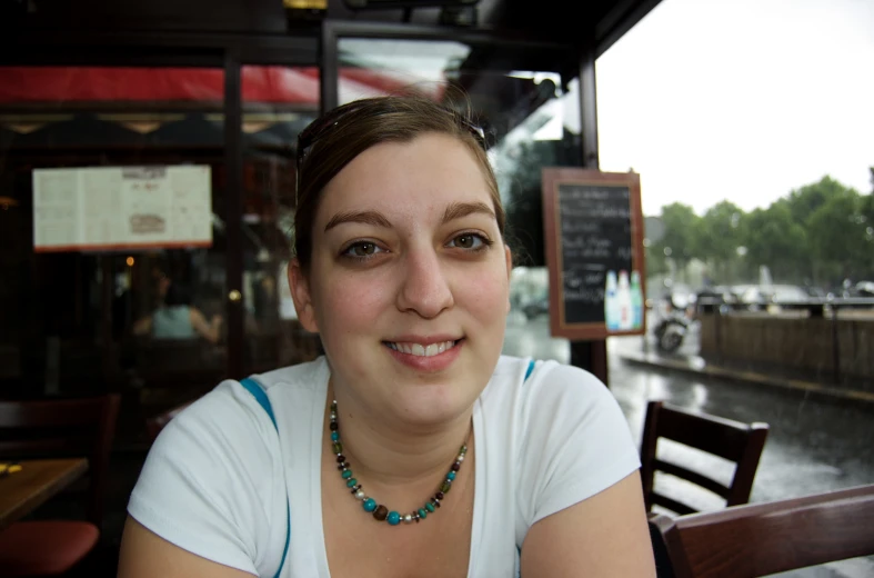 a girl with necklaces on the table in front of the water