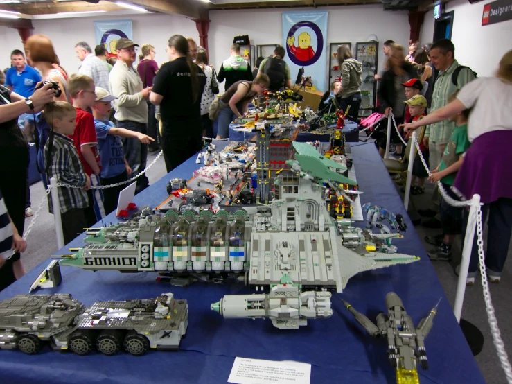 people are gathered around a table with lego models