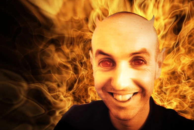 a man wearing a black shirt is smiling in front of some yellow and orange flames
