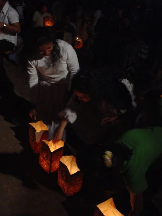 two women standing over some little paper lanterns