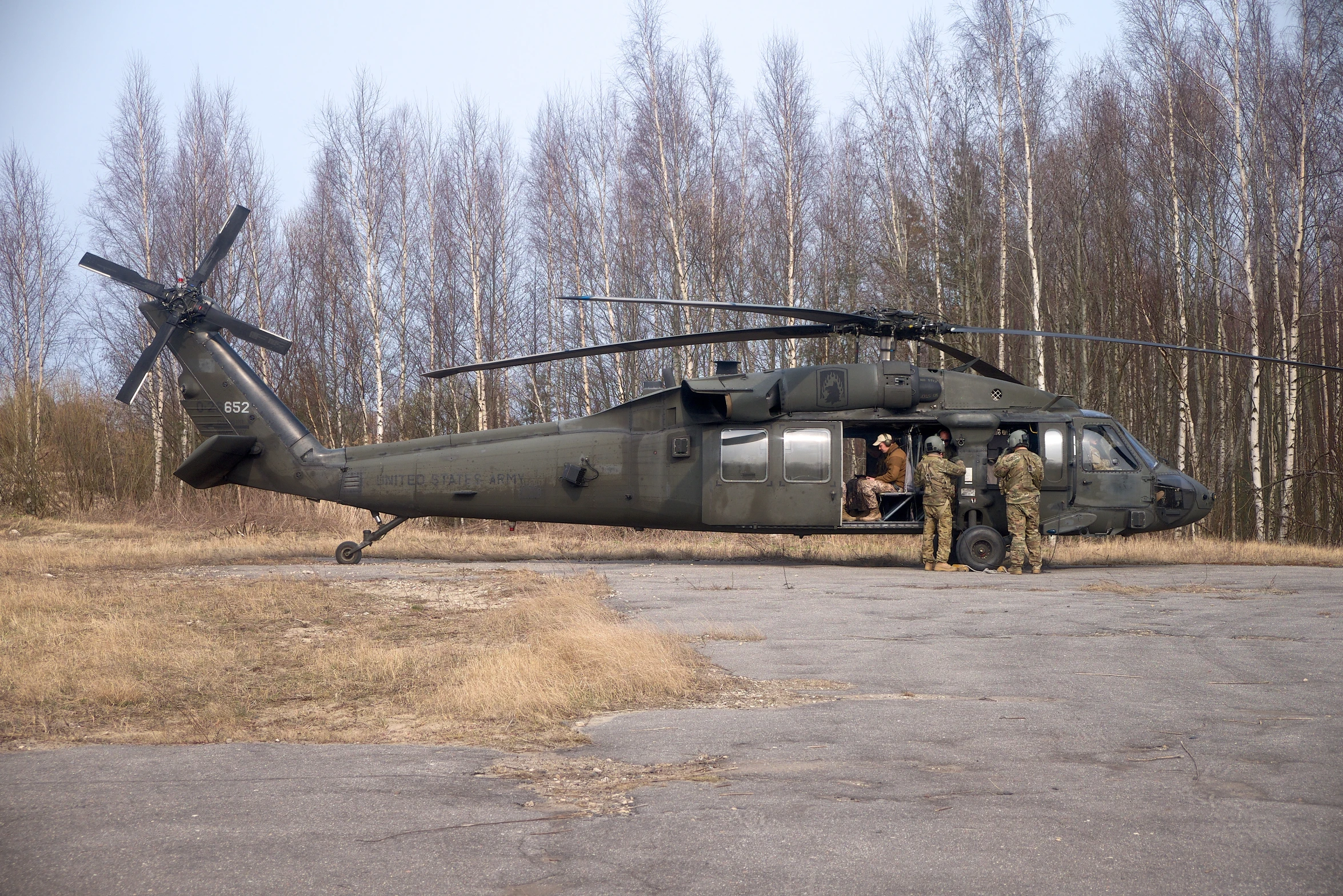 an army helicopter sitting in front of some trees