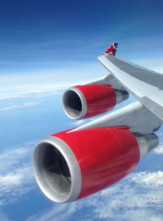 the tail section of an airplane flying above clouds