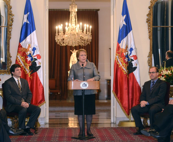 a woman is speaking into microphone in front of three other men