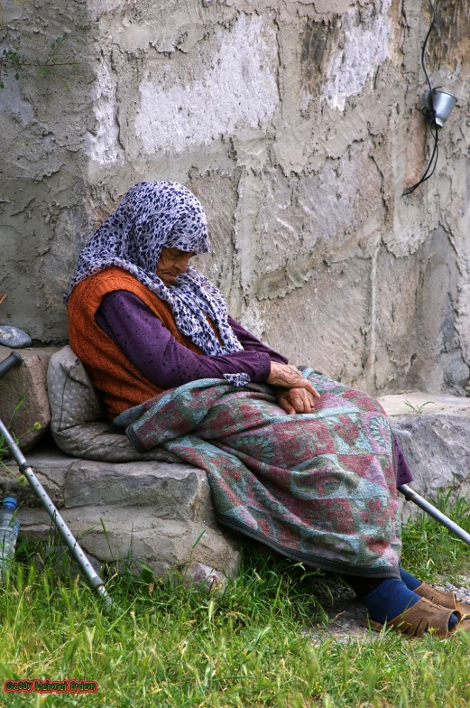 the woman is sitting on a stone bench by her poles