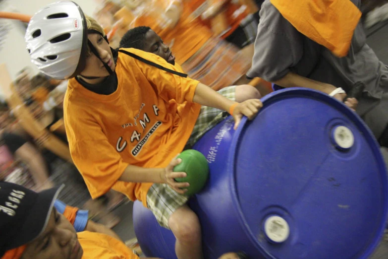 several people in orange shirts with helmets are playing tug of war