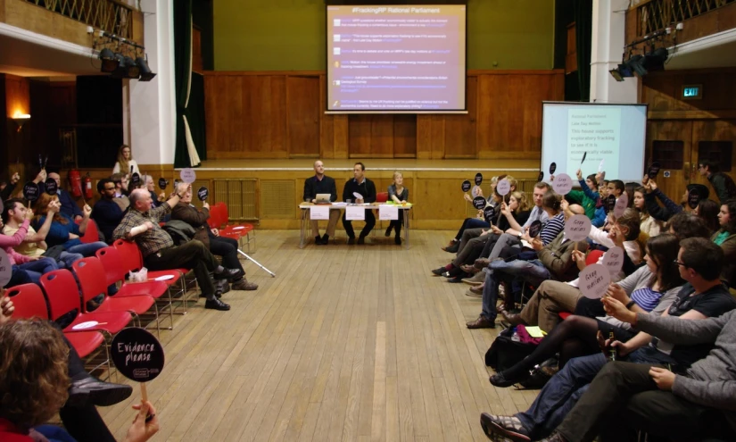 a crowd in a large hall watching a presentation