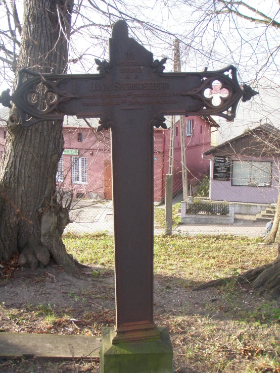 a large cross near a tree in the middle of a field