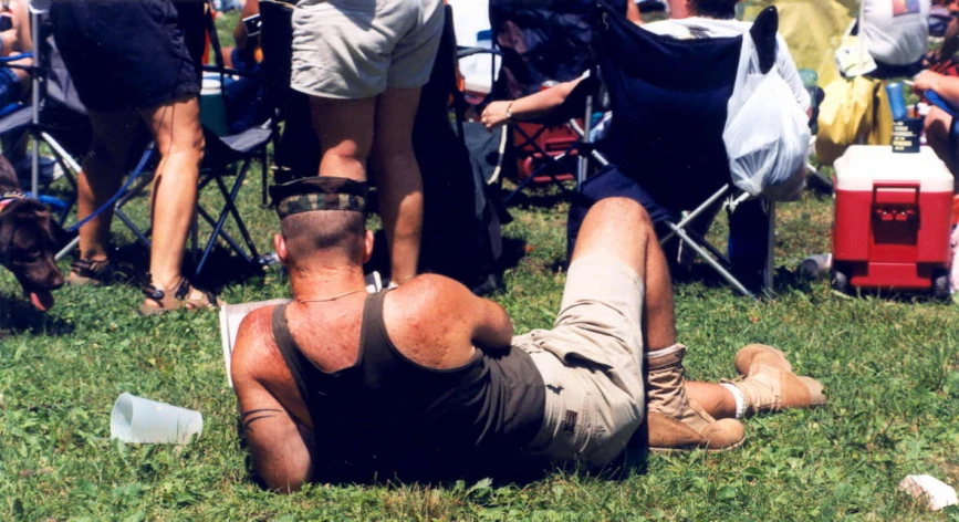 man lying in the grass with his back to the camera