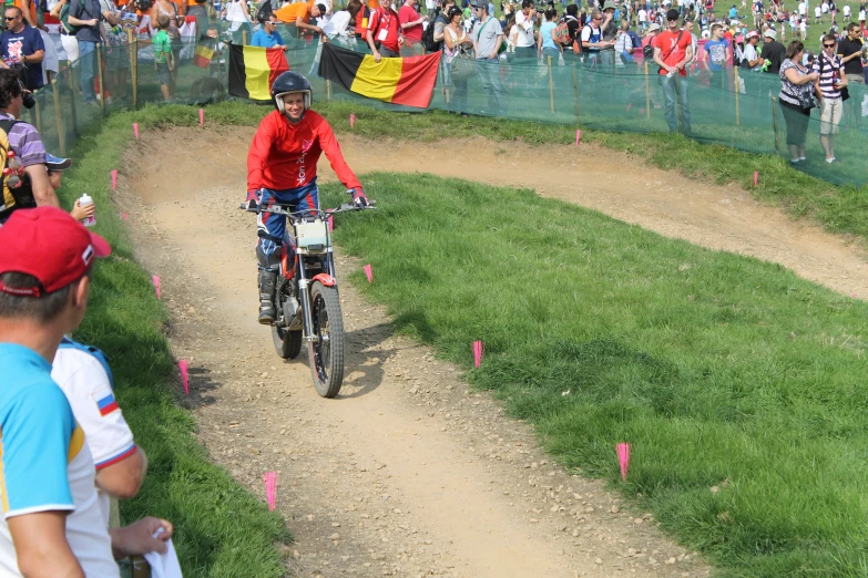 a cyclist wearing a red shirt on a bike at an obstacle