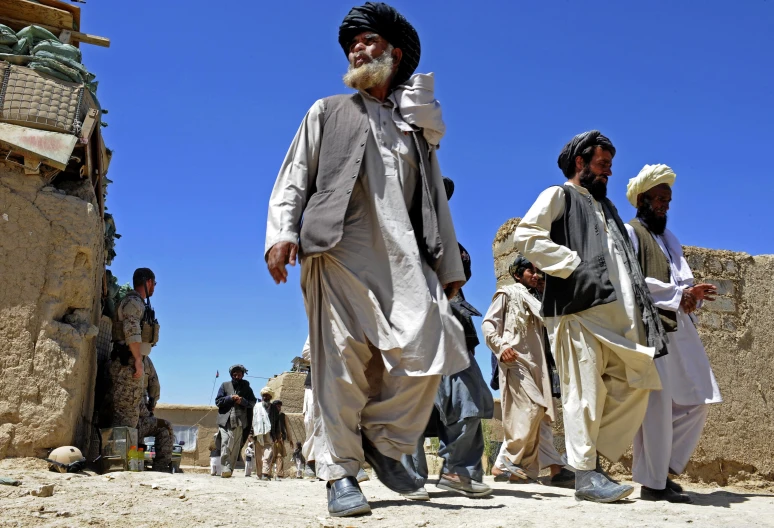 men in white turbans and green hats on dirt and stone