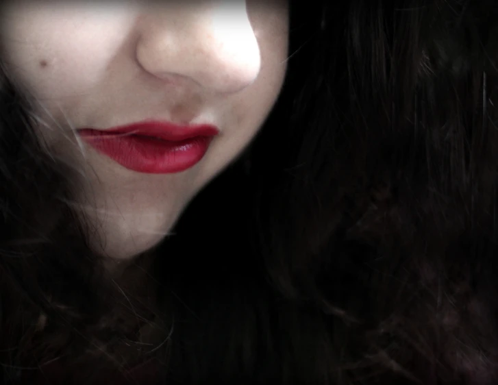 a woman with long dark hair and bright lipstick