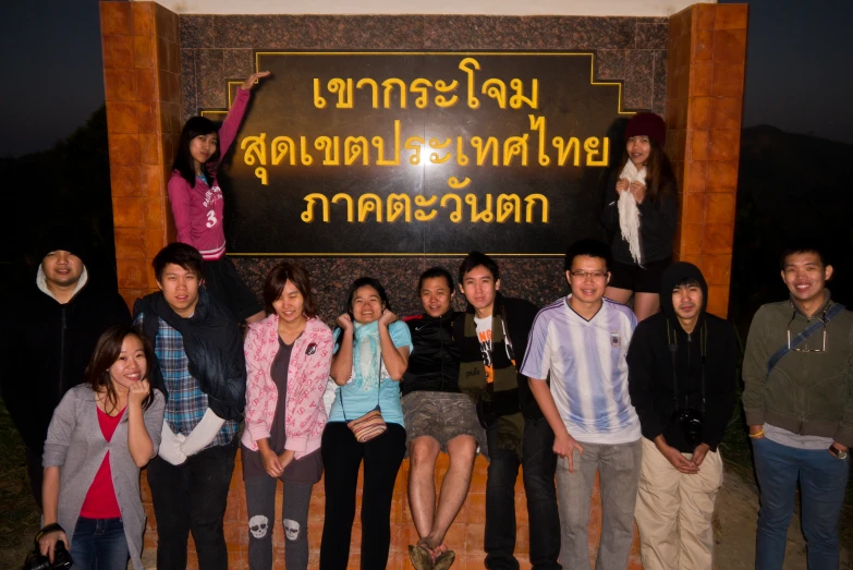 a group of asian people standing in front of a sign