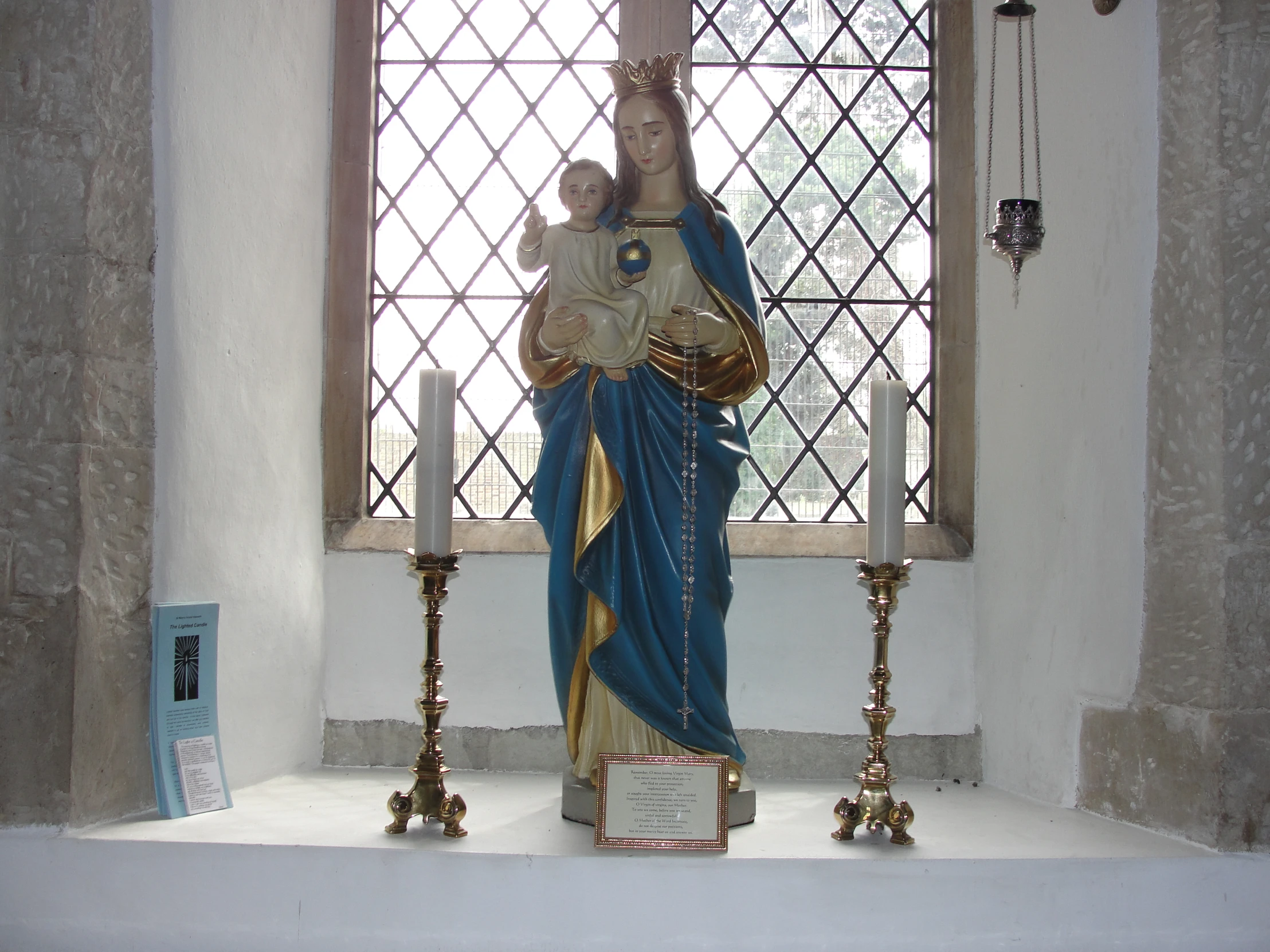 a statue of jesus holding the cross stands in front of a stained glass window